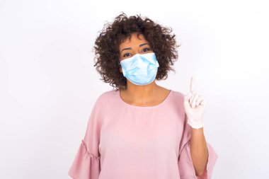 Yüz maskesi takan kadın ve günlük giysiler beyaz stüdyo arka planında izole edilmiş.