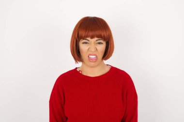 Vücut dili. Gri duvara karşı poz veren, suratını asan, bir şeyden tiksindiğini gösteren, stresli, güzel bir kız..