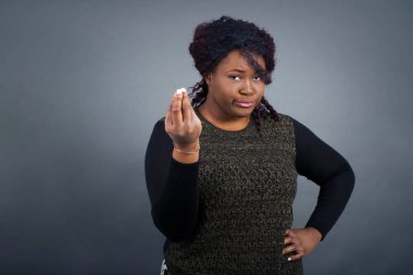 What the hell are you talking about. Shot of frustrated young  african american woman in casual clothes  gesturing with raised hand doing Italian gesture, frowning, being displeased and confused with dumb question.