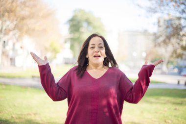 Güzel orta yaşlı Arap kadın parkta avuçlarını gösteriyor.  