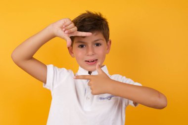 Şirin çocuk sarı duvara çerçeve yapıyor.  