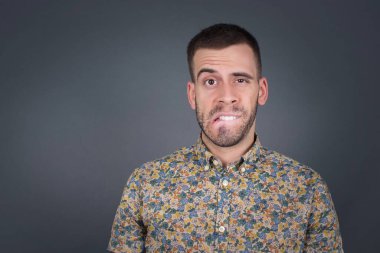 Yakışıklı genç adam gergin ve korkmuş dudaklarını ısıran sabırsız ifadesiyle kameraya bakan, düşünceli. 