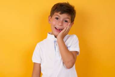 Sarı duvara gülümseyen sevimli çocuk.  