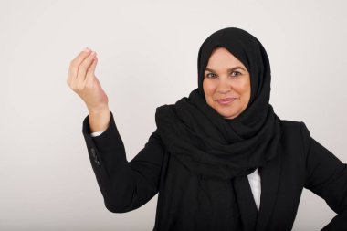 What the hell are you talking about. Shot of frustrated young muslim woman in black hijab gesturing with raised hand doing Italian gesture, frowning, being displeased and confused with dumb question.