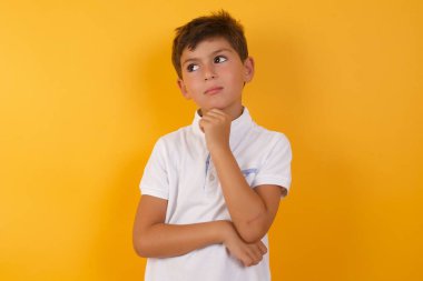 Sarı duvara karşı düşünen tatlı çocuk.  