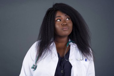 Hoş görünümlü genç Afrikalı Amerikalı kadın doktor, düşünceli bir kenara bakıyor, üniversiteden sonra eylemler planlıyor, ne yapacağını hayal ediyor. Zeki kadın yeni projesini düşünüyor. Boşluğu griye kopyala.