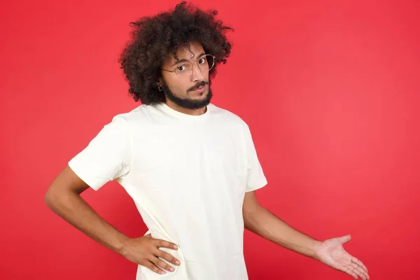 Junger Mann Mit Afro Haaren Zeigt Etwas Gegen Rote Wand — Stockfoto