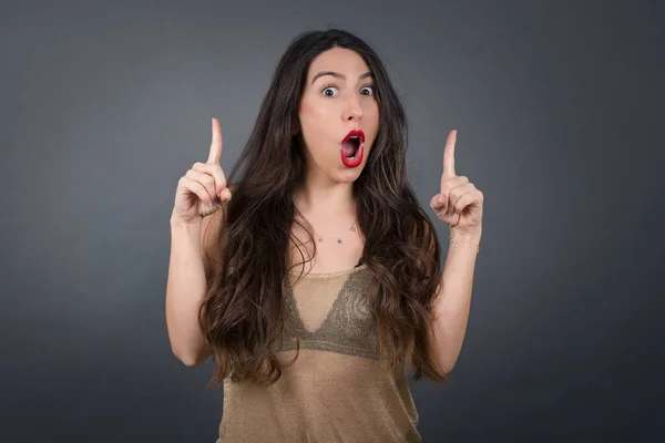 Hermosa Mujer Apuntando Hacia Arriba Contra Fondo Gris —  Fotos de Stock