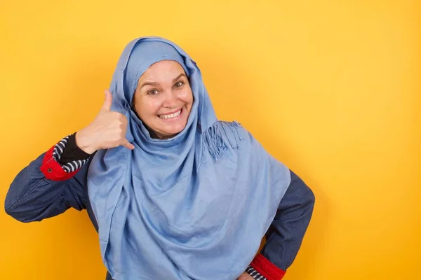 ヒジャブの魅力的な中年イスラム教徒の女性は 電話の会話を模倣し 携帯電話を持っているかのように耳の近くに手を保ち 自信を持って顔の表情を持っています 電話する — ストック写真