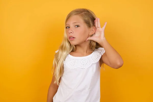 イエロースタジオの背景のリスニングに対するかわいい若い金髪の少女 — ストック写真