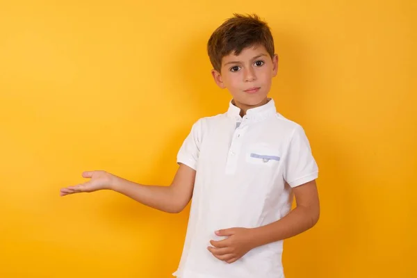 Menino Bonito Mostrando Algo Contra Parede Amarela — Fotografia de Stock