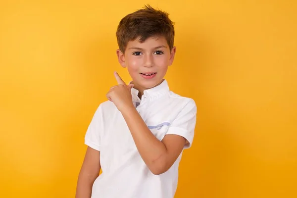 Schattig Jongen Wijzend Terug Tegen Gele Muur — Stockfoto