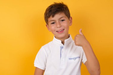 Sarı duvarda başparmağı olan sevimli çocuk.  