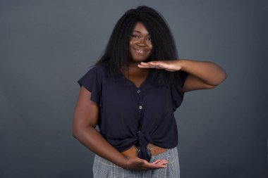 Kışlık süveter giyen genç ve güzel bir kadın. İzole edilmiş bir arka plan. Ellerinde büyük ve büyük bir işaret, ölçü sembolü var. Kameraya bakıp gülümsüyor. Ölçüm konsepti.