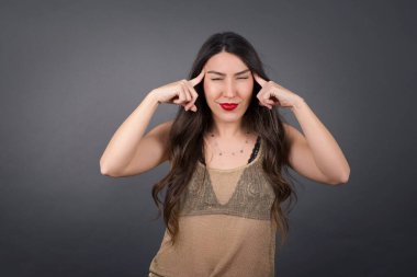 Gri arka planda elleri şakaklarda olan güzel bir kadın..  