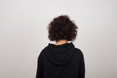 Gri duvara bakan bir kızın arka görüntüsü. Stüdyo Çekimi.