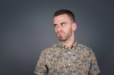 Hoş görünümlü genç bir erkek öğrenci, düşünceli bir şekilde kenara bakıyor, üniversiteden sonra eylemler planlıyor, ne yapacağını hayal ediyor. Zeki adam yeni projesini düşünüyor. Boşluğu griye kopyala.