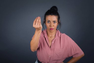 What the hell are you talking about. Shot of frustrated young European woman gesturing with raised hand doing Italian gesture, frowning, being displeased and confused with dumb question.