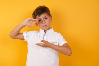 Sarı duvara bir şey gösteren sevimli çocuk.  