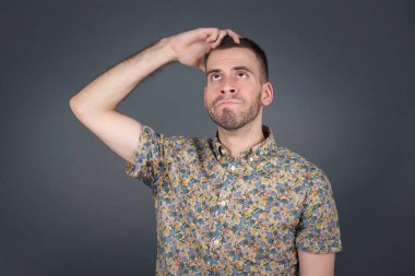 Tüh, ne yaptım ben? Korkmuş ve pişmanlık dolu ifadesiyle el ele tutuşan yakışıklı bir adam. Gri arka planda dikilen günlük giysiler giyiyor..