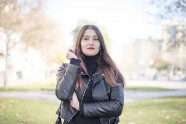 Genç ve güzel bir kadın parktaki kameraya bakıyor.