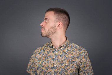 Sağlıklı, saf cilde sahip ciddi bir adamın profili, üzerinde fotokopi alanı olan gri stüdyo duvarının üzerinde yürümeye hazır düşünceli bir ifadeye sahiptir.. 