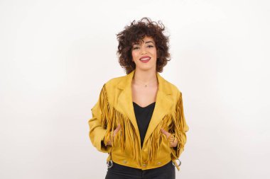 Güven ve iş kavramı. Çekici, başarılı bir genç kızın portresi. Gri duvarın önünde el ele tutuşurken kendinden emin bir ifadeyle gülümsüyor..