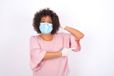 Yüz maskesi takan kadın ve günlük kıyafetler beyaz stüdyo arka planında izole edilmiş kasları gösteriyor.