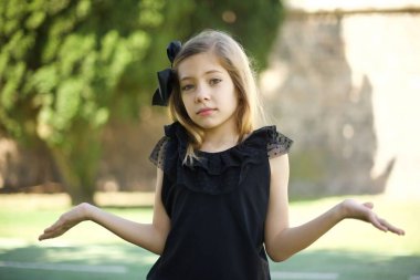 Kafası karışmış, siyah elbiseli, omuzlarını silkip 