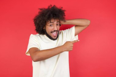 Kızıl duvarı işaret eden afro saçlı genç adam.   