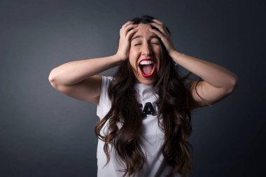 Güzel bir kadın bağırıyor. Gri arkaplanda duruyor. 