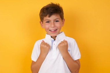 Sarı duvarda yumrukları olan sevimli bir çocuk.  