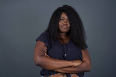 Güzel, kendine güvenen, neşeli, Afro-Amerikan kadının belinde geniş bir gülümseme, kollarını kavuşturuyor.