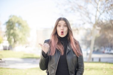 Genç ve güzel bir kadın parkta bir şey gösteriyor.