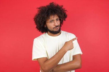 Kızıl duvarı işaret eden afro saçlı genç adam.   