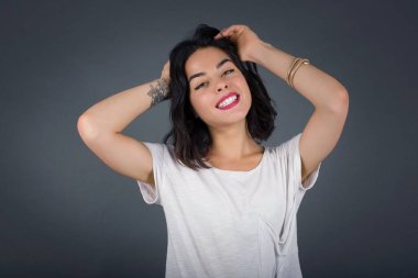 Güven ve cinsel ilişki konsepti. Çekici bir genç kızın portresi, el ele tutuşurken kendinden emin bir ifadeyle geniş bir gülümseme. Gri arkaplanda duruyor. 