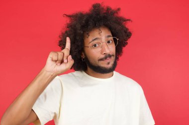 Kızıl duvarı işaret eden afro saçlı genç adam. 