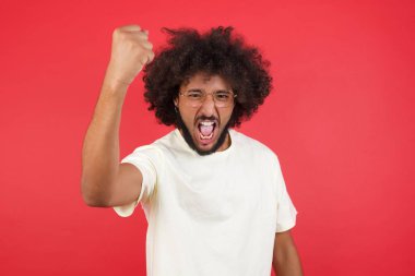 Kızıl duvarda yumruğunu gösteren afro saçlı genç adam.   