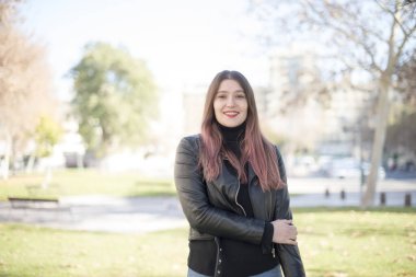 Genç ve güzel bir kadın parktaki kameraya bakıyor. 