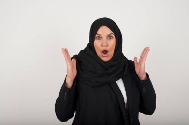 Sürpriz konsept. Siyah tesettürlü, hayretler içinde bir Müslüman kadın portresi. İnanması güç, ağzı açık, yüzü yakın, saçları örgülü bir kadın. Olumlu duygu yüz ifadesi vücut dili.