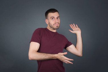 Yakışıklı, beyaz bir genç iki eliyle tuhaf bir şey gösterip 