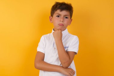 Sarı duvara karşı düşünen tatlı çocuk.  