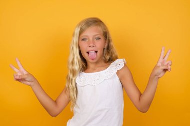 Sarı arka planda zafer işareti yapan tatlı kız. 