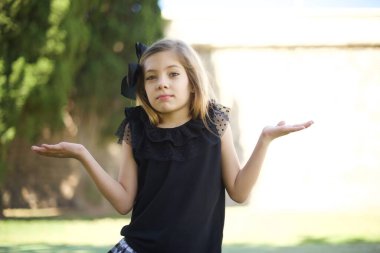 Kafası karışmış, kolları açık, omuzlarını silkip 