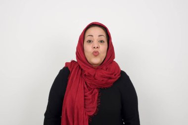 Hoş görünümlü, olgun Müslüman bir kadın. Dudaklarını öpecek gibi tutuyor. Mutlu bir ifadesi var, suratını buruşturmuş.. 