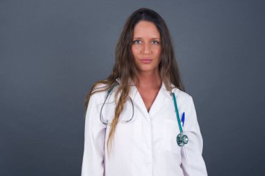 Güzel genç doktor kadın modelin stüdyo çekimini kapatın. Kameraya sevimli bir gülümsemeyle bakarken içeriğiniz için boş fotokopi duvarına karşı poz verin..