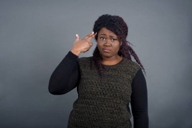 Mutsuz sarışın Afro-Amerikan kadın, sıradan kıyafetler içinde, silah atışı taklidi yapıyor, intihar hareketi yapıyor, parmaklarını şakakların üzerinde tutuyor..