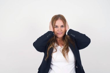 Orta yaşlı, kulaklarını elleriyle tıkayan bir kadın hard rock ya da yüksek sesli müzik dinlemek istemiyor. Orta yaşlı kadın gürültüyü ya da gürültüyü görmezden geliyor ya da elleriyle kulaklarını kapatıyor. Sokakta yüksek seslerden kaçınıyor..