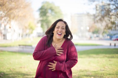 Güzel orta yaşlı Arap kadın parkta gülüyor.  