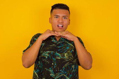 Beyaz tişörtlü İspanyol bir erkeğin stüdyoda aylak aylak dolaşıp zıplamasına çok şaşırdım. Renkli arka planda dans eden ve elleriyle çeneye dokunan sevimli adam iyi vakit geçiriyor..